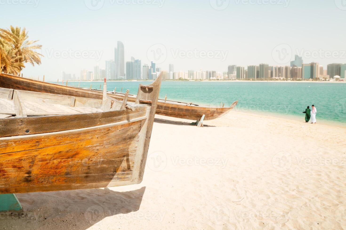 Abu Dhabi skyline and old traditional fishing boats in Heritage Village in Abu Dhabi in United Arab Emirates UAE. Couple tourist enjoy beach and visit sightseeing travel destination in UAE. photo