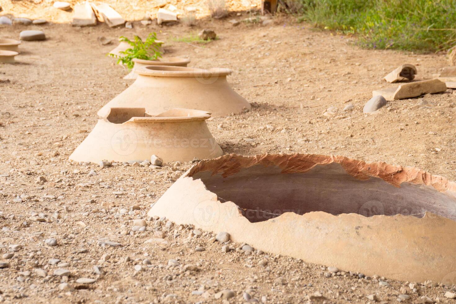 Clay wine vessels embedded in earth beneath wooden shelter at Armaziskhevi site, part of an ancient wine making cellar Mtskheta region, Georgia. photo