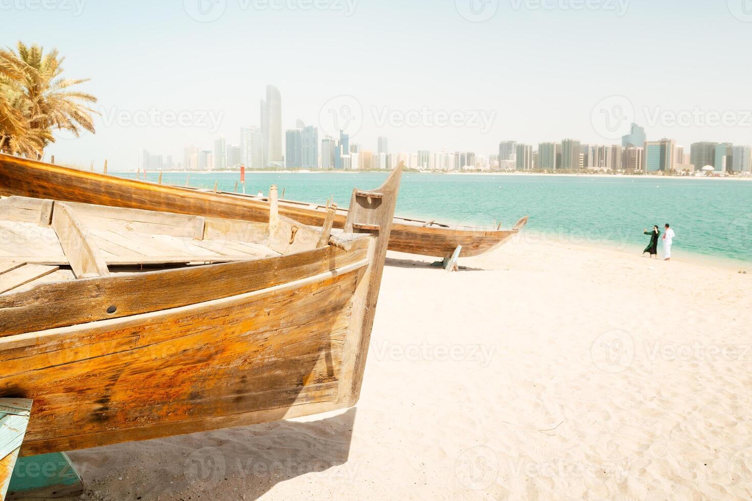Abu Dhabi skyline and old traditional fishing boats in Heritage Village in Abu Dhabi in United Arab Emirates UAE. Couple tourist enjoy beach and visit sightseeing travel destination in UAE photo