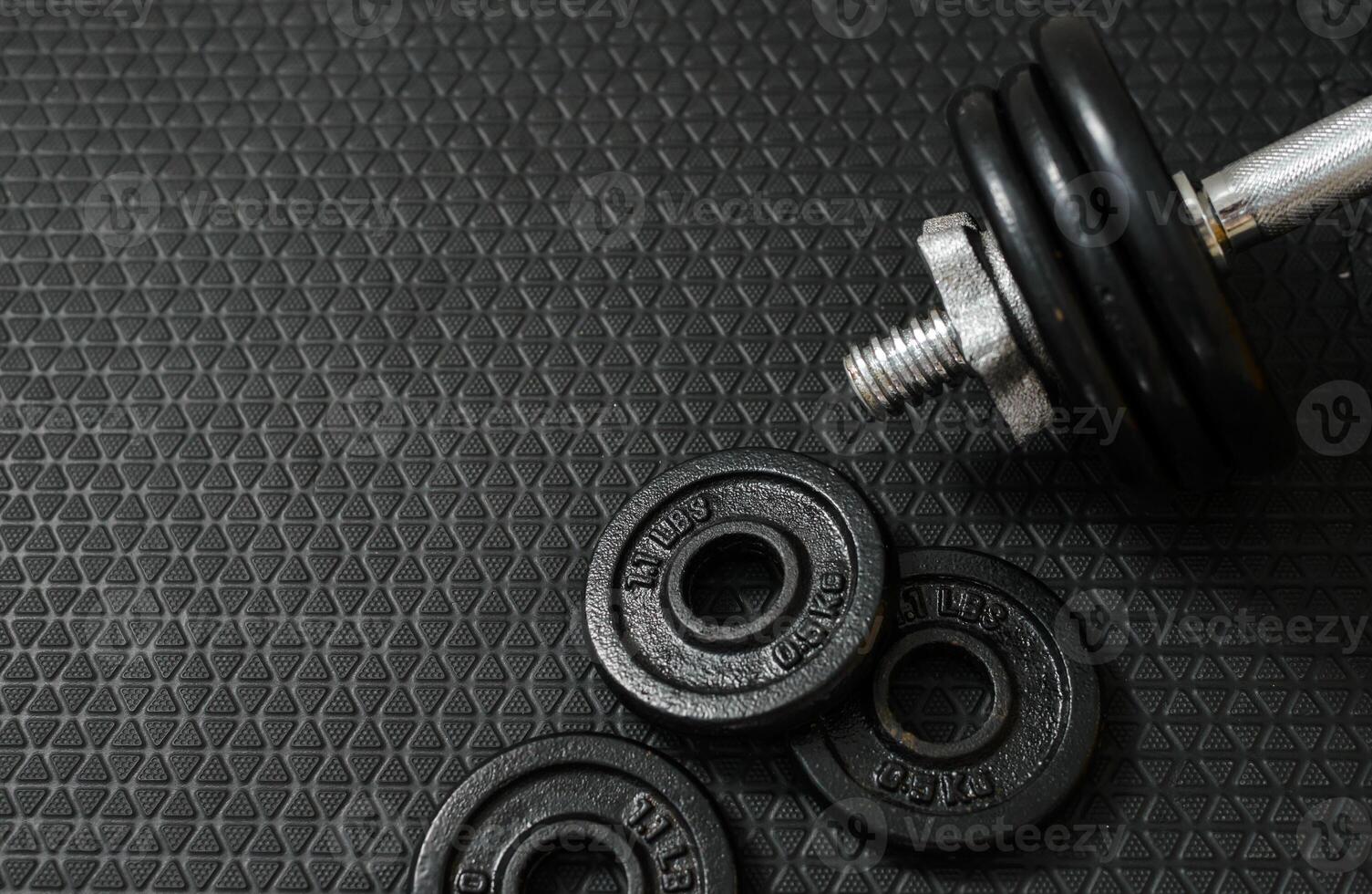Iron dumbbells or weights on black floor with copy space for text on left photo
