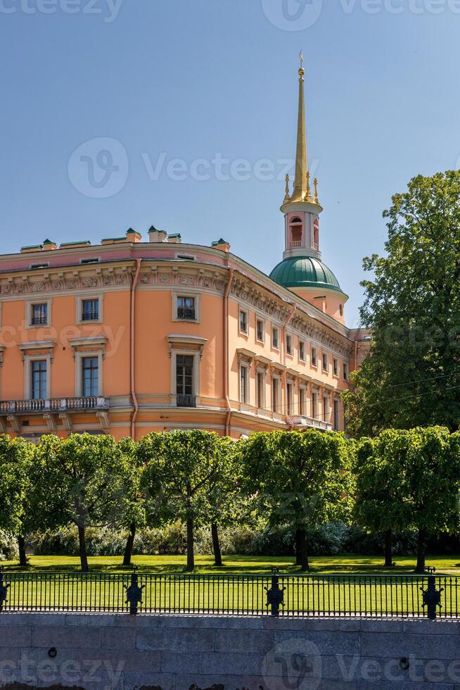 Mikhailovsky Castle, surrounded by well-maintained greenery and a fence, under a clear blue sky. photo