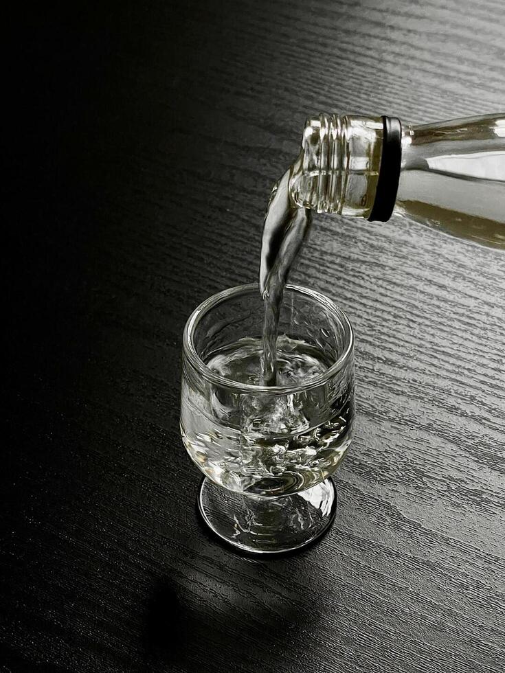 A bottle of vodka being poured into a glass photo