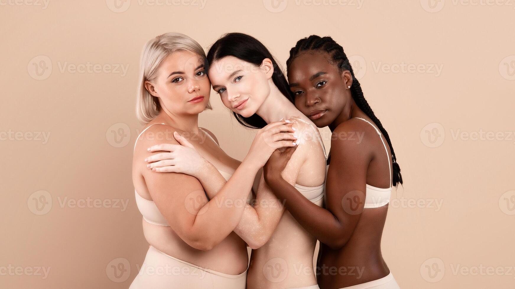 Group Of Beautiful Multiracial Body Positive Women Posing In Underwear Over Beige Studio Background, Young Females With Different Appearances And Skin Types Embracing And Looking At Camera, Free Space photo