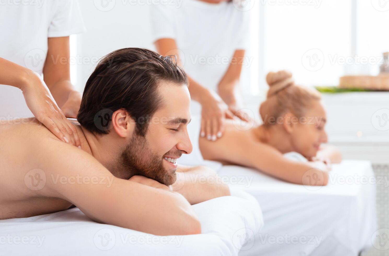 Happy Spouses Enjoying Massage At Spa Lying With Eyes Closed During Relaxing Procedure At Spa Salon, Focus On Relaxed Husband. Couples Massage, Body Relaxation And Beauty Treatment Concept photo