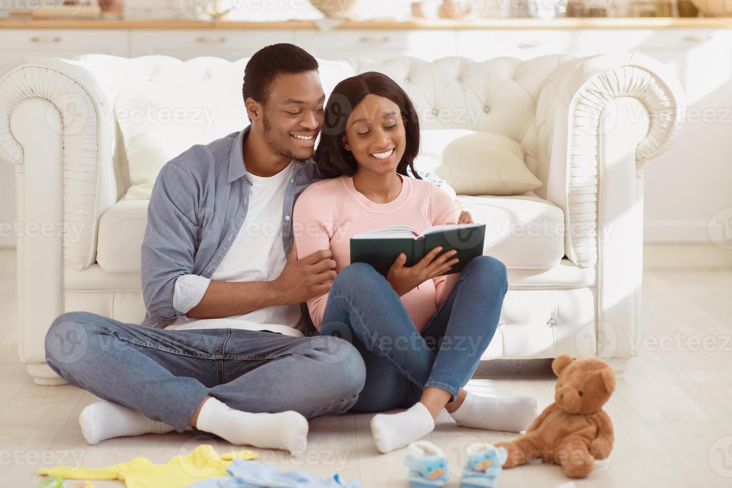Preparing for childbirth concept. Pregnant black couple making checklist of baby things before going to maternity hospital. Loving husband taking notes of child stuff for birthing center photo