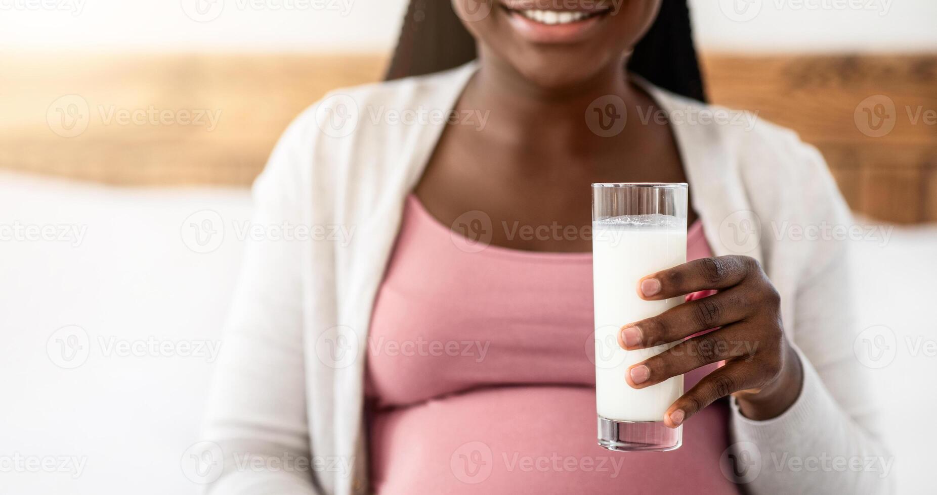 Pregnant African American Woman Enjoying Glass Of Milk At Home, Happy Black Expectant Lady Drinking Healthy Calcium Drink And Smiling, Relaxing In Bedroom, Cropped Image With Free Space, Closeup photo