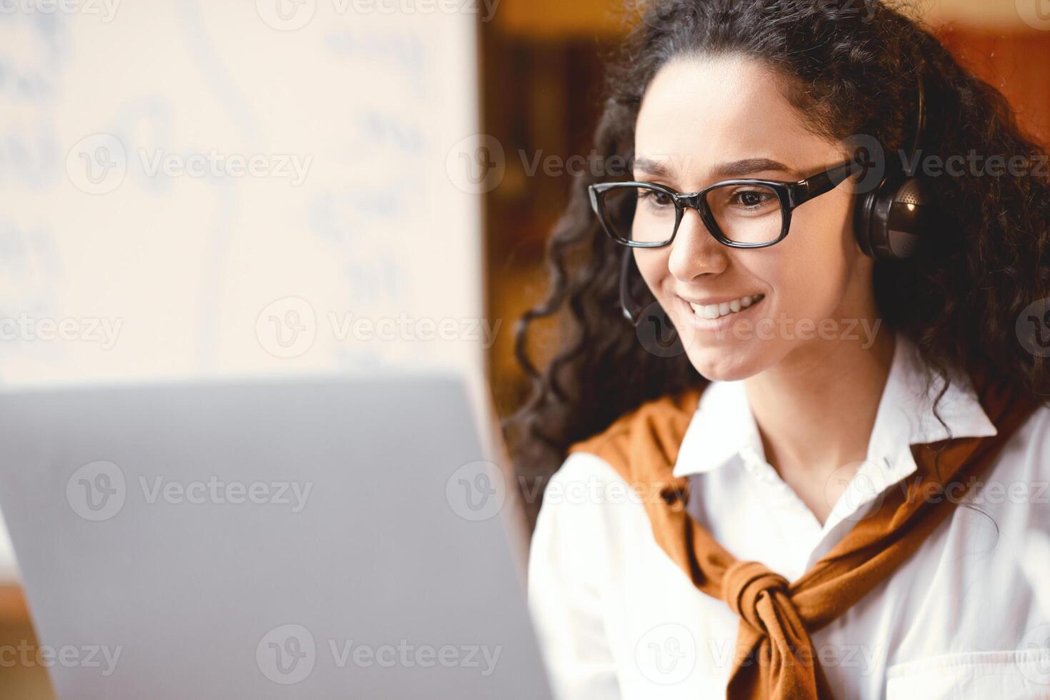 Professional Manager. Closeup portrait of confident woman wearing headset and eyeglasses, having videocall or online briefing on laptop computer, talking to colleagues or consulting client photo