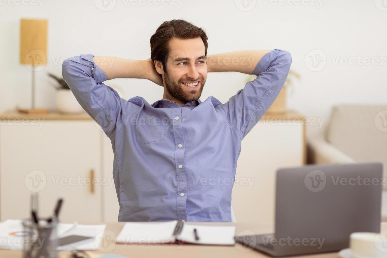 Carefree Businessman Relaxing Sitting Holding Hands Behind Head At Workplace In Office. Cheerful Entrepreneur Resting Sitting At Laptop. Successful Business Career Concept photo