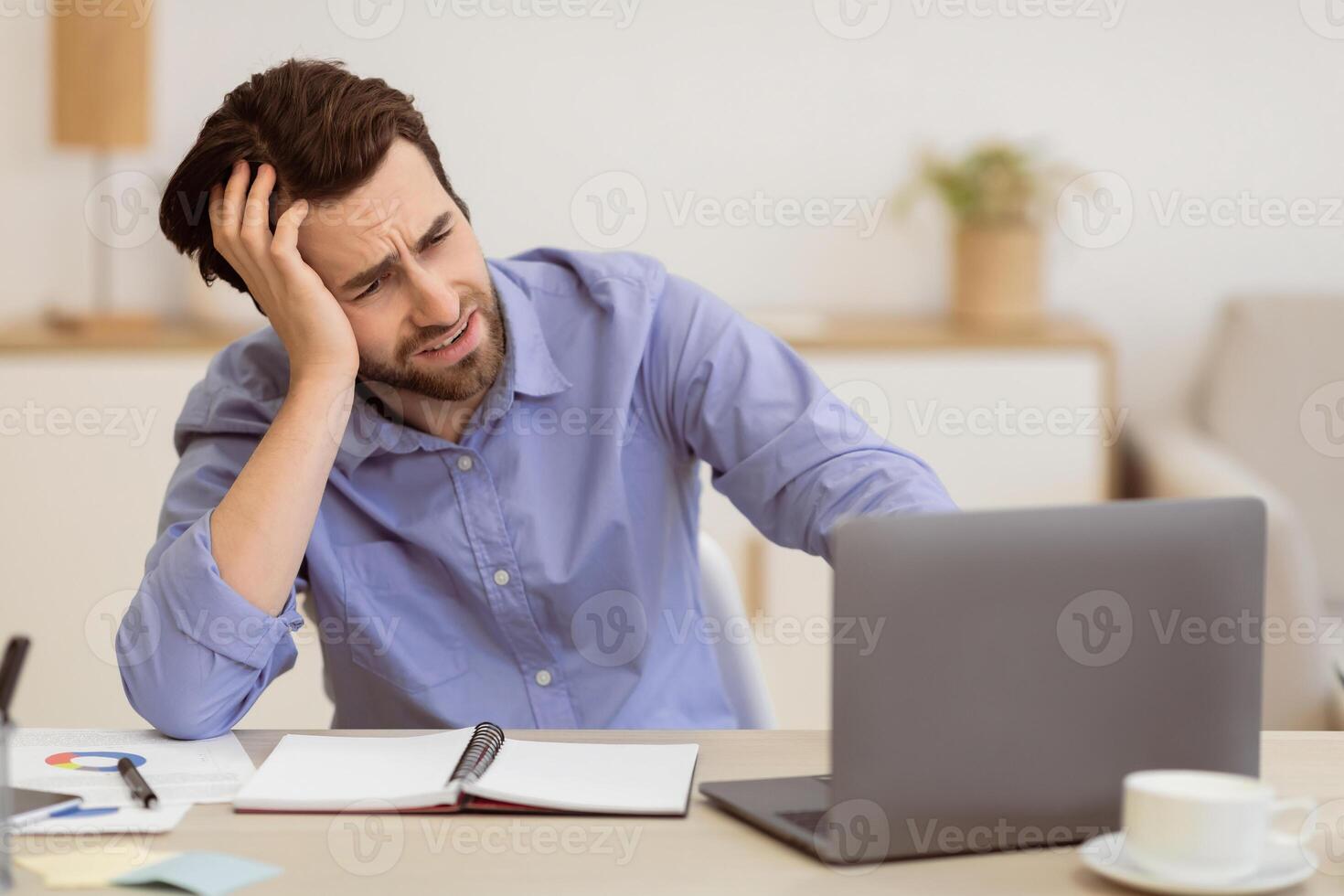 Unhappy Employee. Bored Man Sitting At Laptop Computer Looking Aside At Screen And Procrastinating At Workplace In Modern Office. Procrastination Problem Concept. Selective Focus photo
