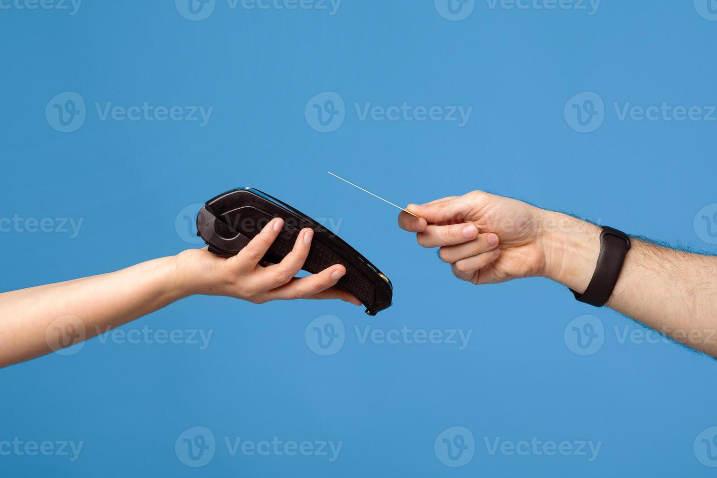 Unrecognizable male and female hands with credit card and money terminal over blue studio background. Young guy making contactless payment during coronavirus pandemic, closeup photo