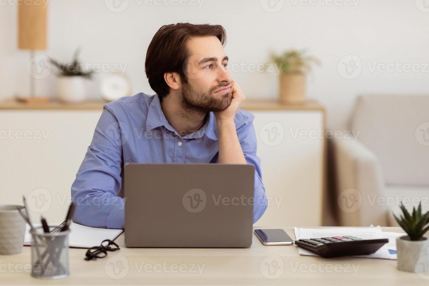 Boring Job. Bored Businessman Sitting At Laptop Computer And Looking Aside Procrastinating In Modern Office. Procrastination Problem At Workplace Concept. Selective Focus photo