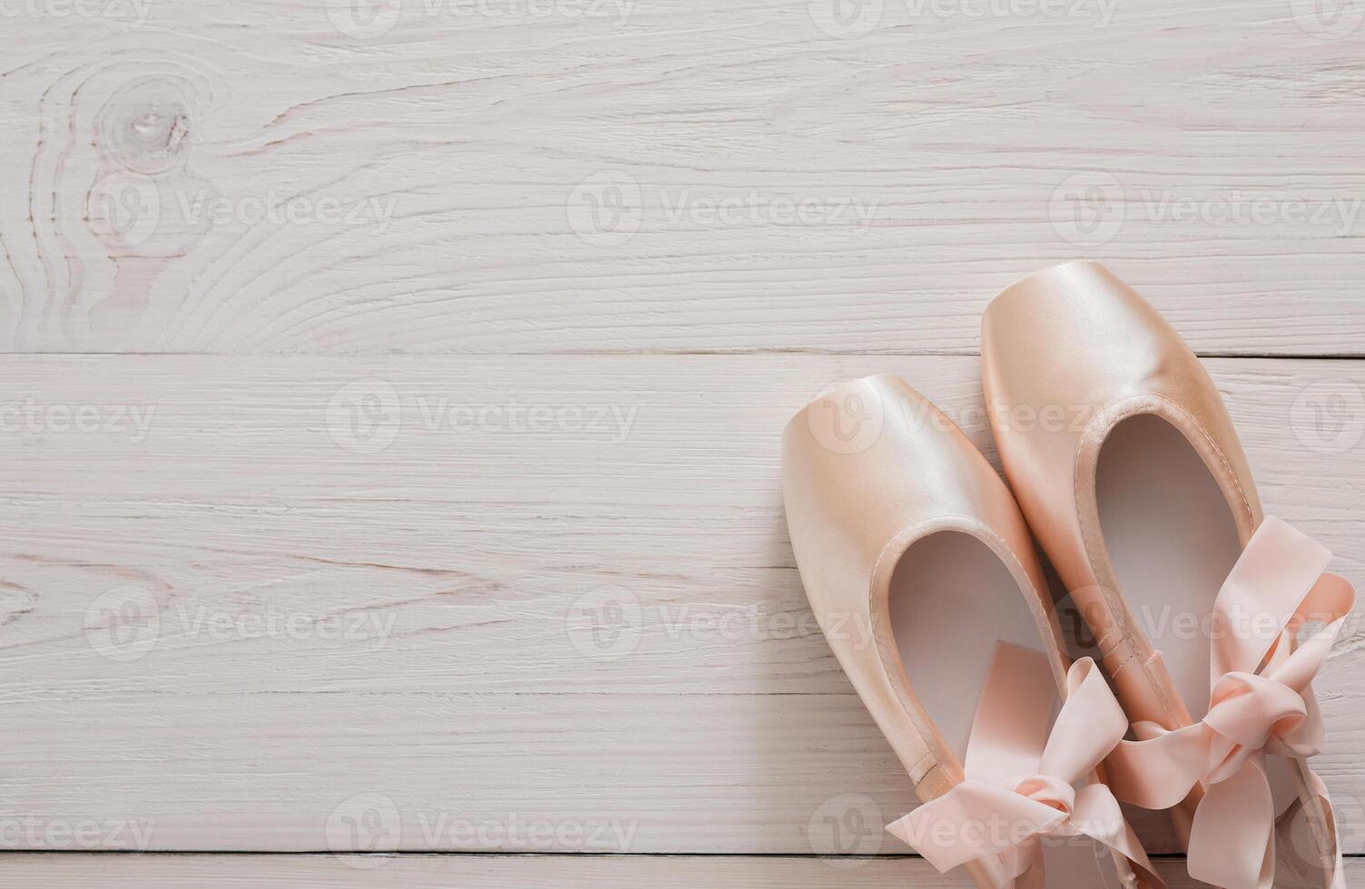 Pastel pink ballet shoes background. New pointe shoes with satin ribbon lay on white rustic shubby chic wood, top view with copy space photo