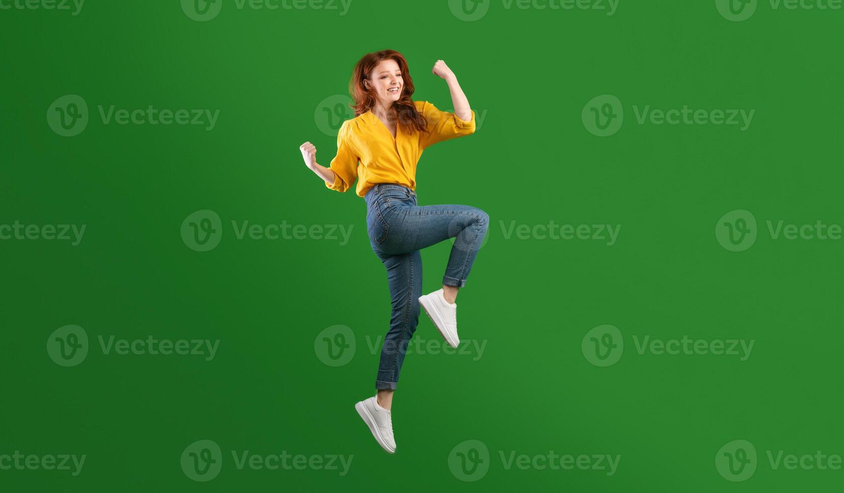 Winner. Happy Millennial Girl Jumping Shaking Fists In Joy Celebrating Victory Over Green Background. Studio Shot, Empty Space photo