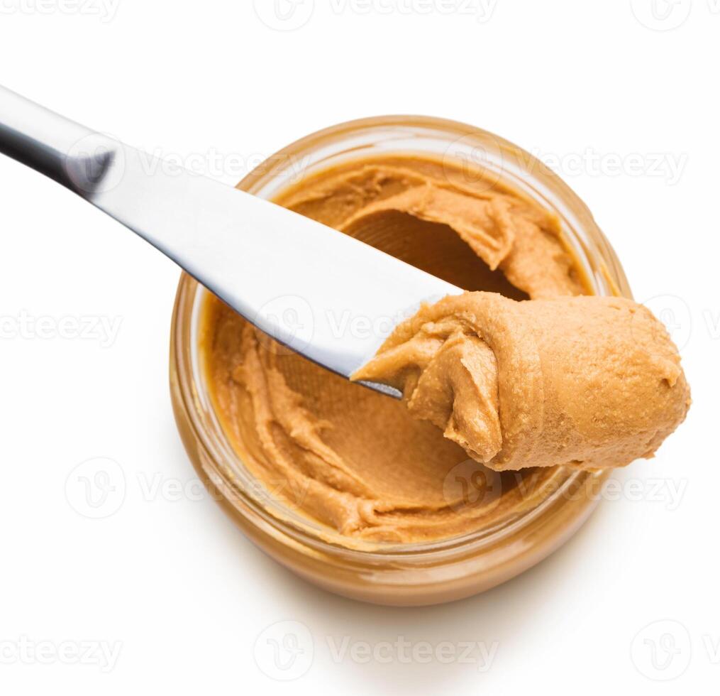 Jar with peanut butter and knife butter smear isolated on white background. Ameriacan dessert concept photo