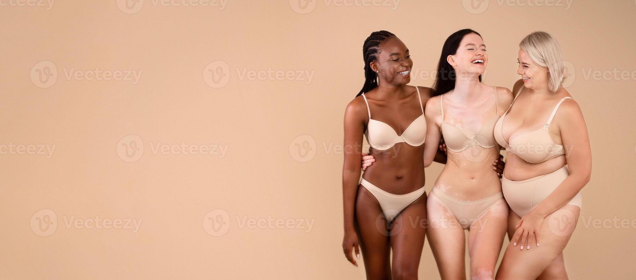 Portrait Of Body Positive Women Of Different Nationalities And Weight Types Posing On Beige Background, Full Length Shot Of Beautiful Black Female, Plus Size Woman, And Lady With Vitiligo In Underwear photo