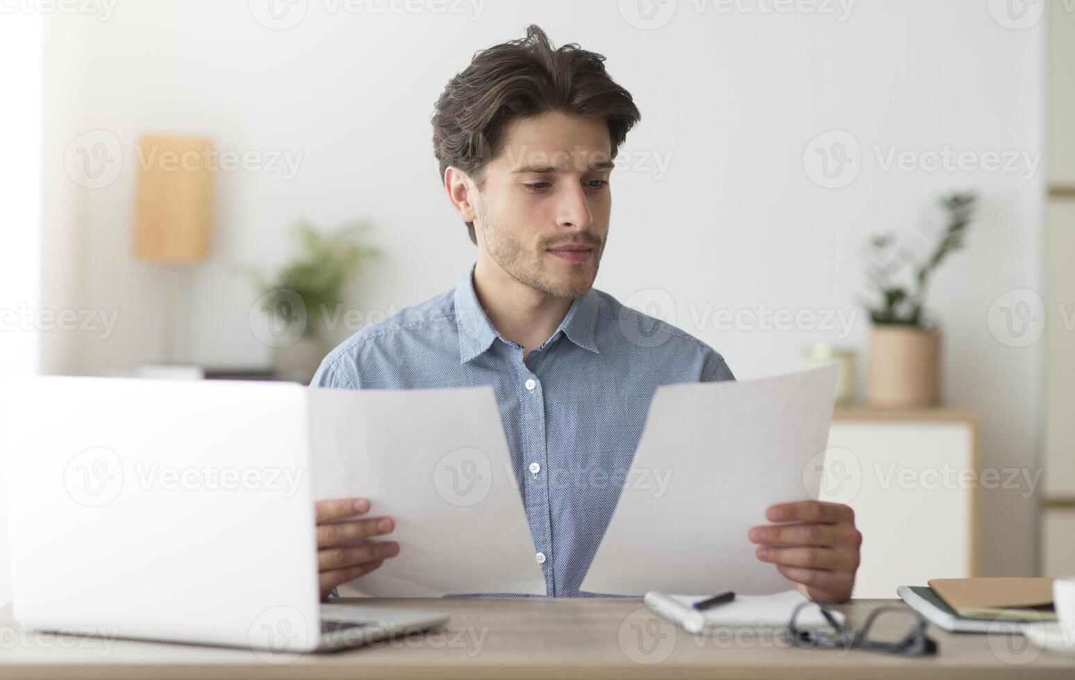Serious Business Man Working With Papers Sitting At Laptop In Modern Office. Selective Focus photo
