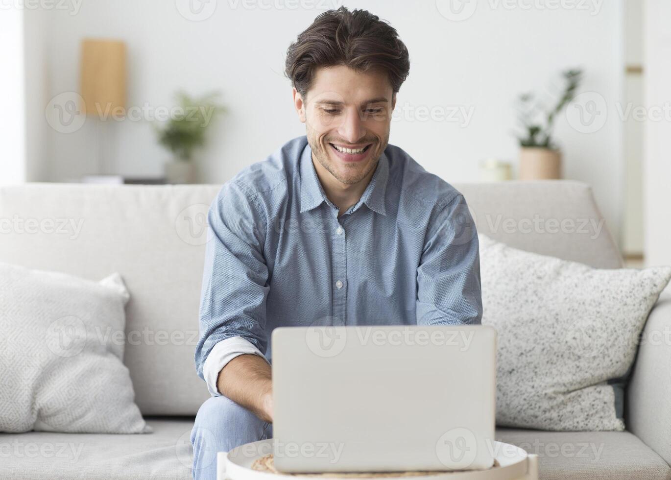Freelance Career. Smiling Man Working On Laptop Computer Sitting On Sofa At Home. photo