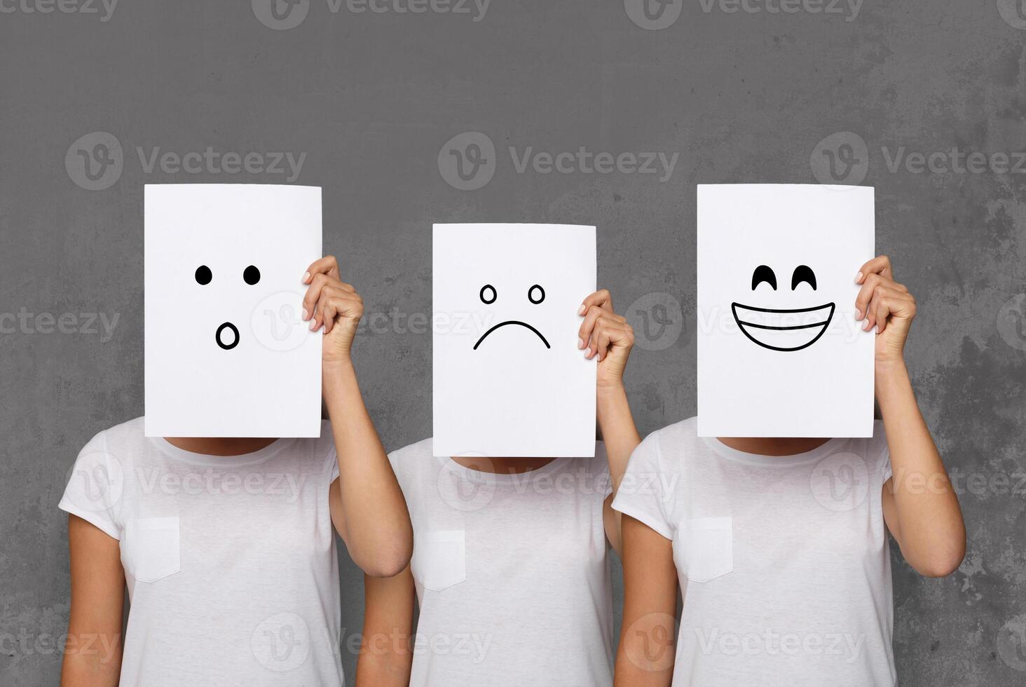 Emotions set. Girl hiding face behind signboard with drawn smileys. Collage of surprised, happy and sad emoticons. photo