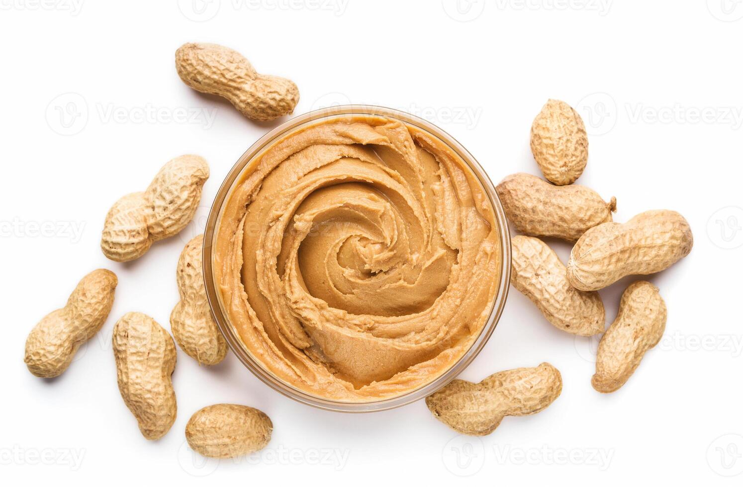 Bowl of peanut butter and unshelled scattered peanuts on white background, isolated photo
