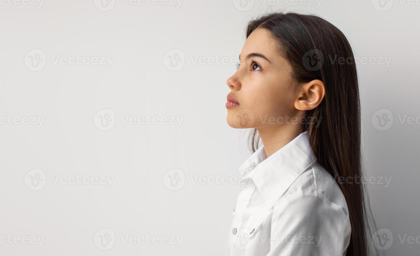 Side View Portrait Of Serious Arabic Preteen Girl Posing Looking Aside Standing Near Empty Space For Text On White Studio Background, Panorama. Schoolgirl Kid Advertising Offer photo