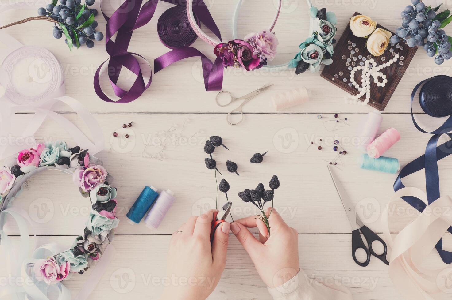 Master making handmade jewelry, top view. Needlewoman workplace with plastic beads, flowers and tools for creating accessories photo