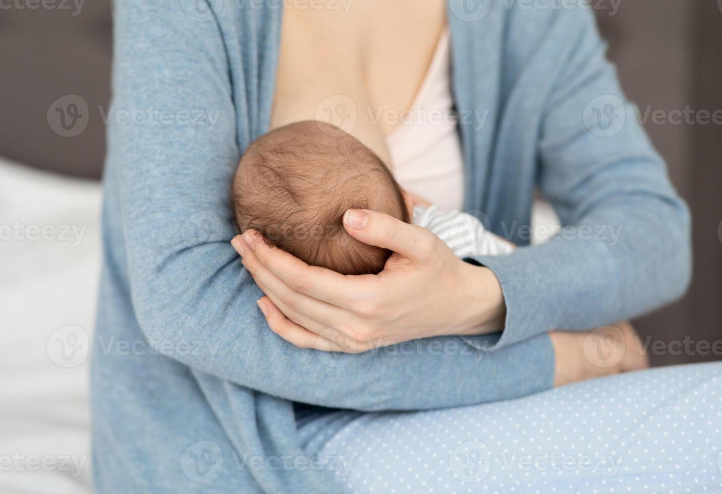 Unrecognizable Mother Holding And Breastfeeding Newborn Baby At Home, Loving Mom Tenderly Holding Head Of Her Infant Child During Lactation, Bonding With Small Kid, Closeup Shot, Cropped photo