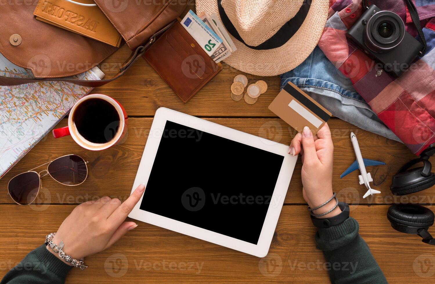 Booking tickets online by tablet and credit card top view. Preparing for vacation, travel and modern technologies concept. Holding device with blank screen, mockup photo