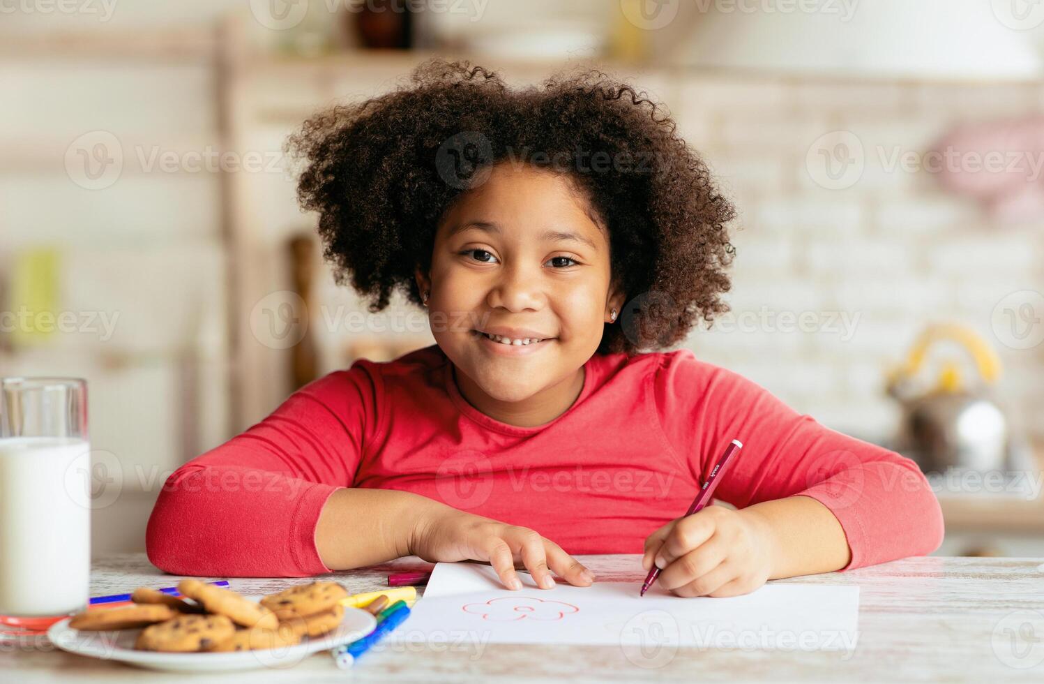 Portrait Of Happy Cute Little Black Girl Drawing In Kitchen, Adorable African American Female Child Sitting At Table With Cookies And Milk And Smiling At Camera, Closeup Shot With Free Space photo