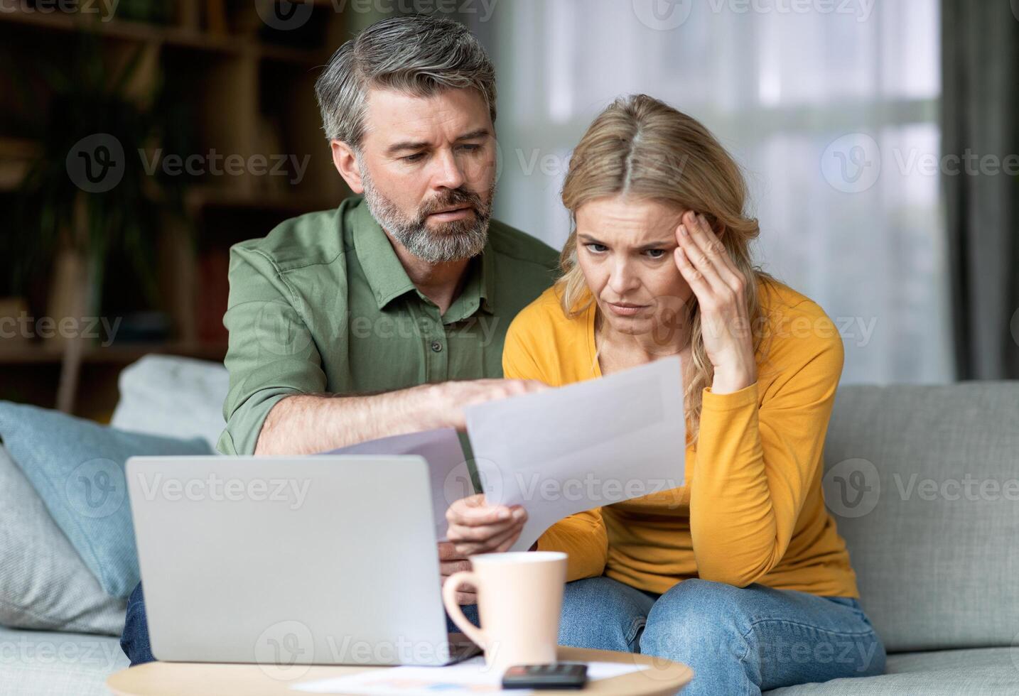 Stressed Middle Aged Spouses Checking Financial Papers At Home, Upset Mature Husband And Wife Looking At Loan Documents, Calculating Family Budget While Suffering Financial Crisis, Closeup photo