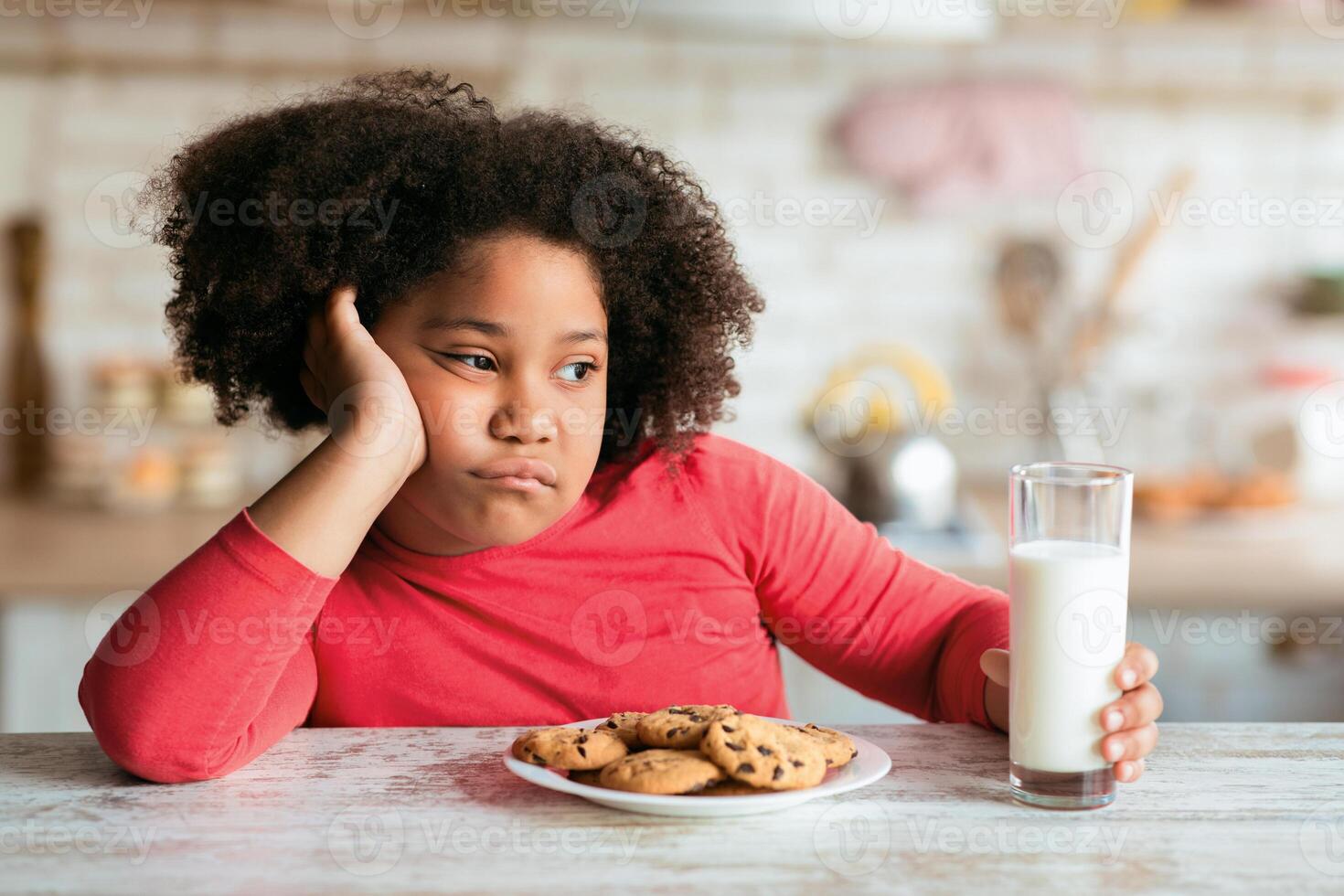 Bored Black Little Girl Sitting At Table With Milk And Cookies, Refuse To Eat Breakfast, Unhappy Kid Resting Head On Hand And Looking Away, Naughty Child Without Appetite Sitting In Kitchen, Closeup photo