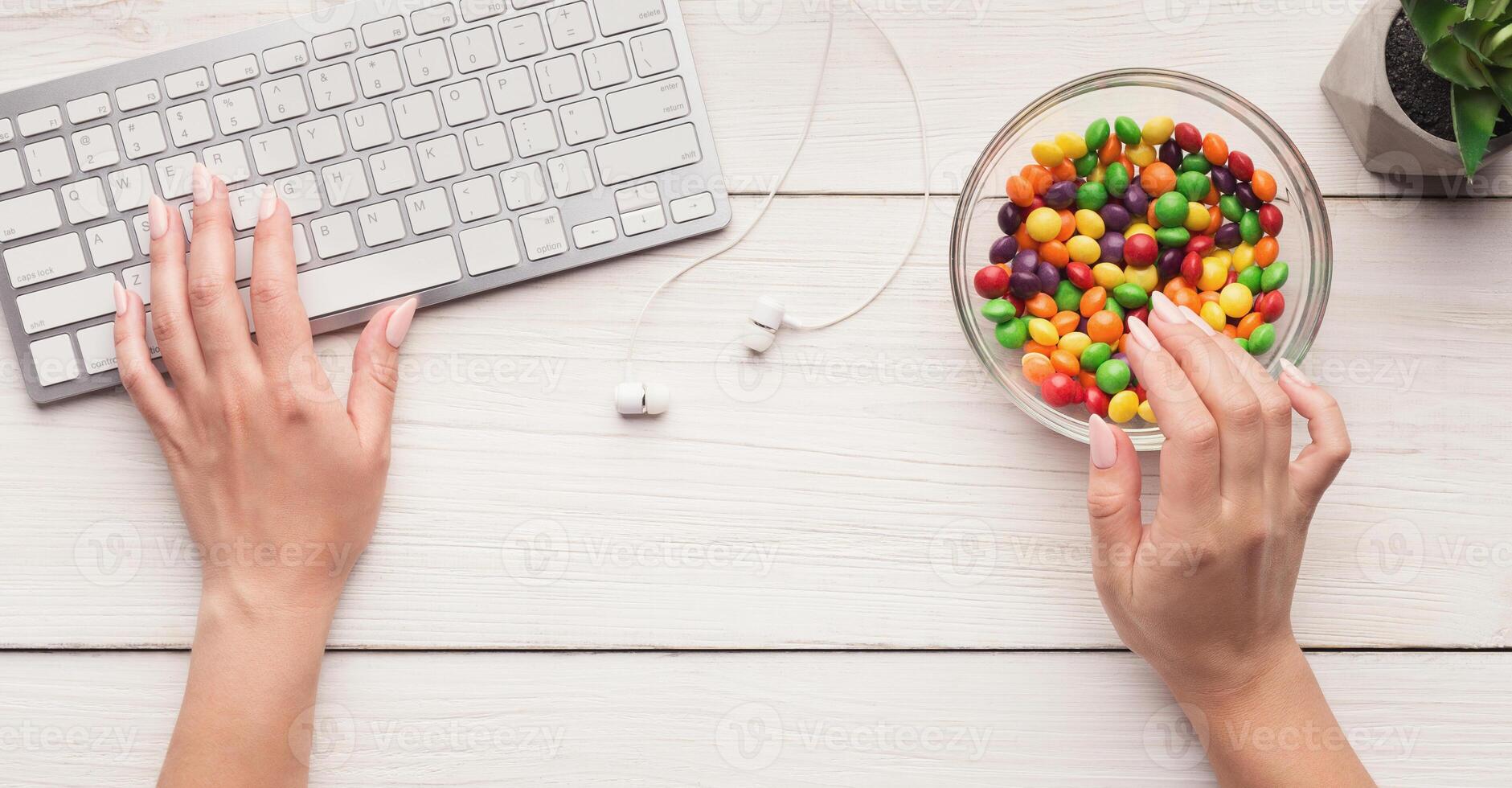 Sweet snack at work, bowl of candies at office table, top view, copy space photo