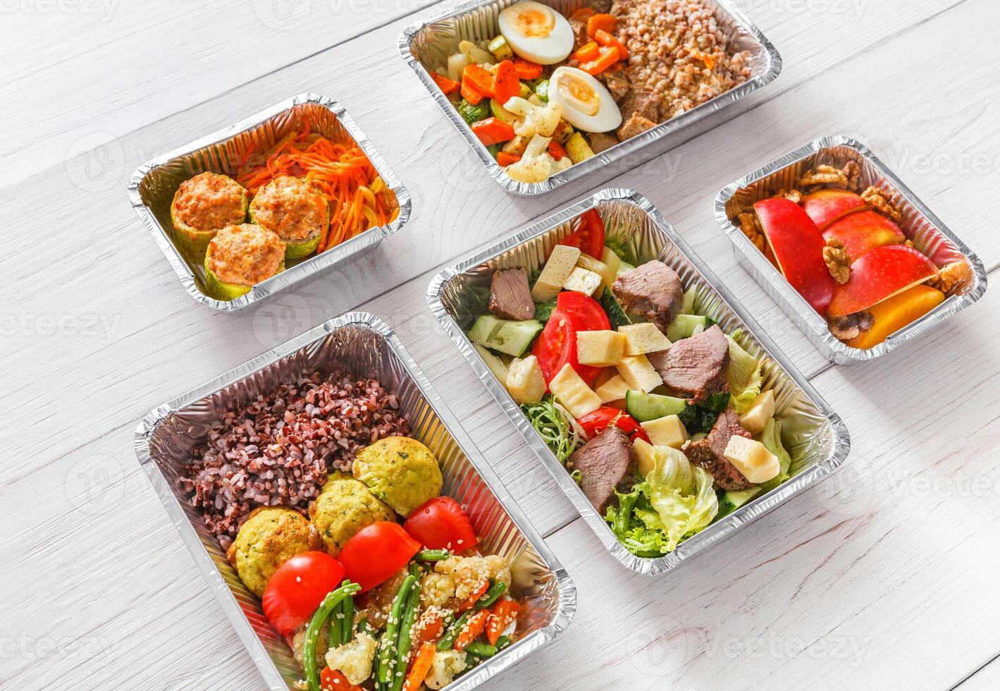 Healthy restaurant food. Chef prepared diet daily meals delivery. Fitness nutrition, vegetables, meat and fruits in foil boxes, cutlery in craft package on wood photo