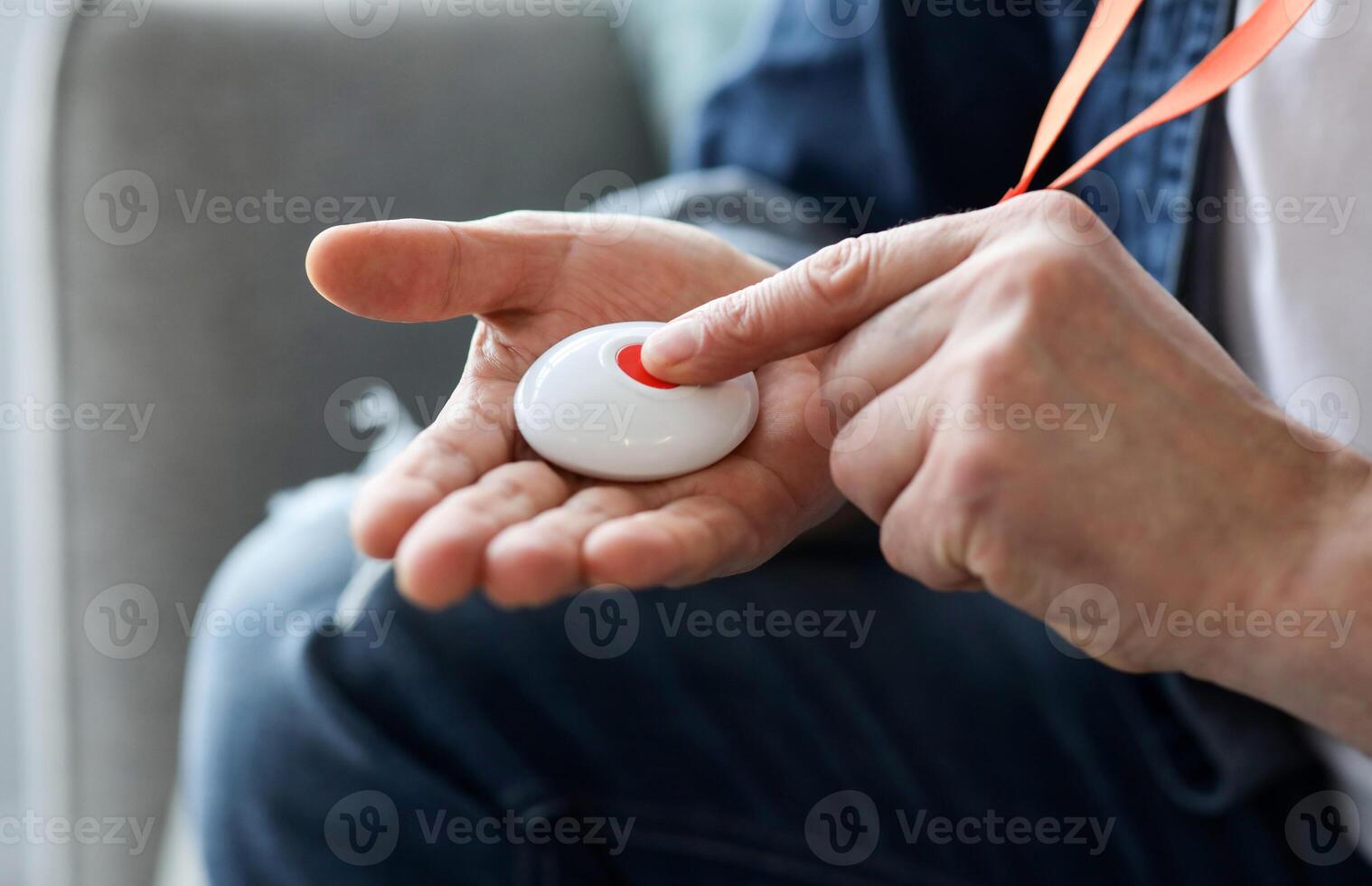 Closeup of man's hand pressing alarm button for emergency on his chest, home interior. Unrecognizable mature man pushing panic button on emergency equipment for elderly people, cropped photo