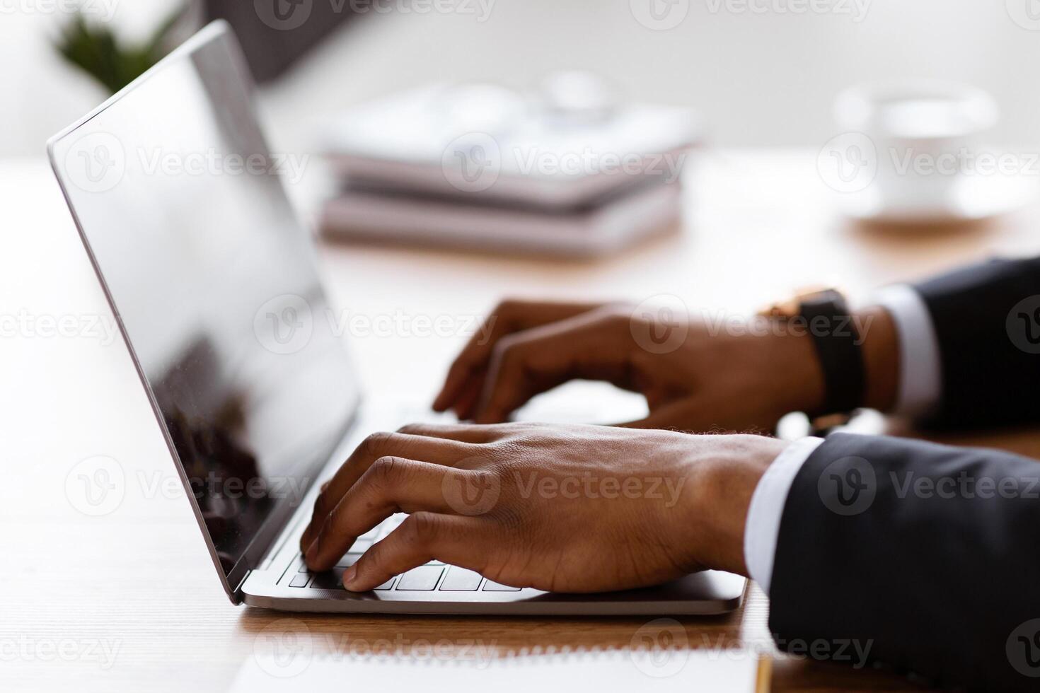 Side view of unrecognizable black manager typing on modern laptop, sending emails or working on business project, office interior, cropped. African american businessman hands on keyboard, closeup photo