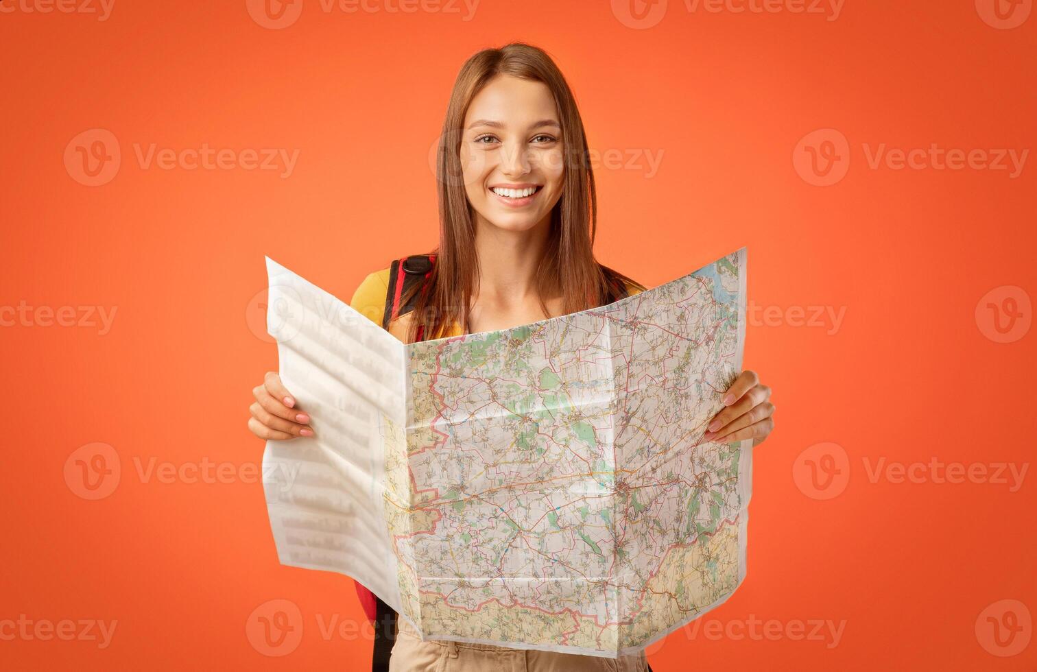 Happy girl tourist holding city map, yellow studio background photo