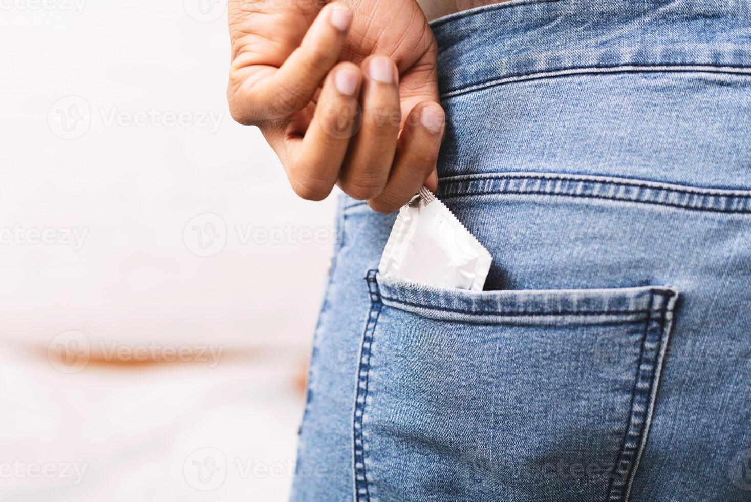 Safety sex concept. Unrecognizable black man taking condom from jeans back pocket, copy space photo