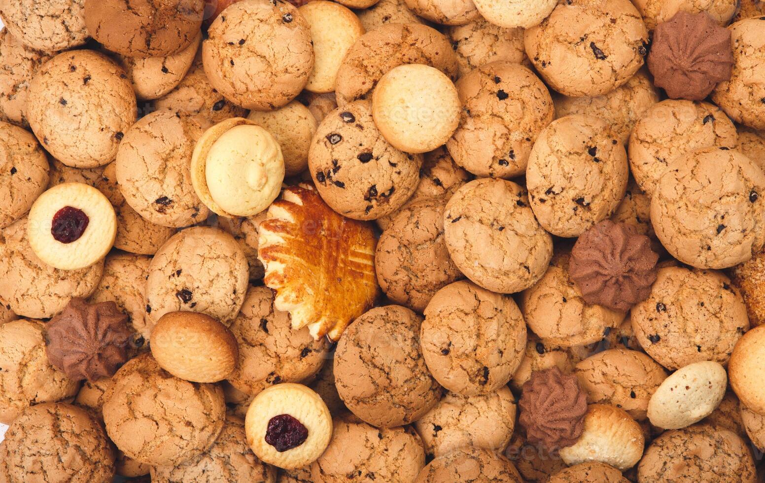 Cookies background. Sweet chocolate chips biscuits, shortbread and cookies with jam texture background. Oatmeal, chocolated drops and other sweets. Dessert, sweets for tea. Fattening sweets concept photo