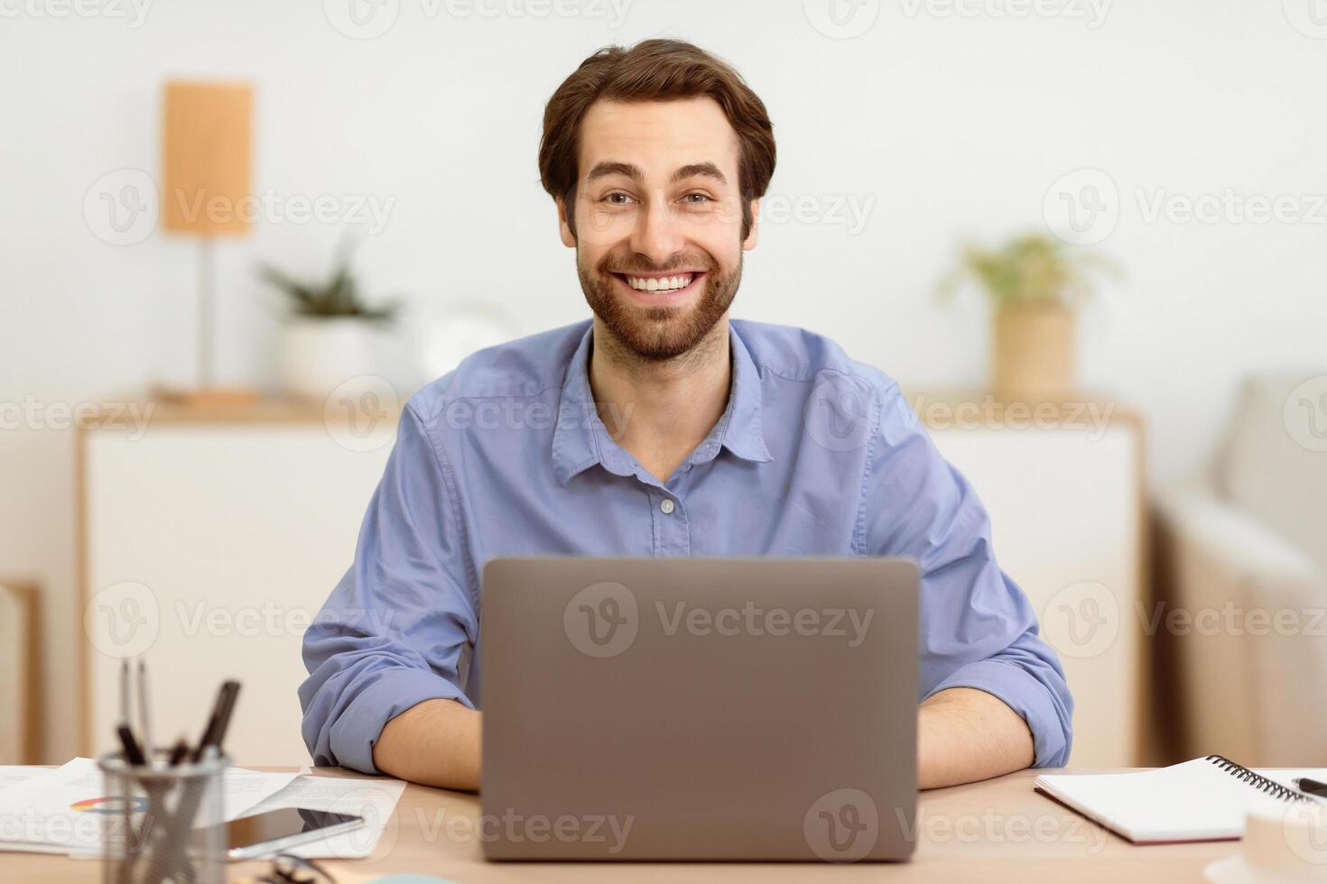Excited Businessman At Laptop Computer Working Online Posing Smiling To Camera Sitting At Desk In Home Office. Remote Freelance Work, Distance Job And Successful Entrepreneurship Career photo