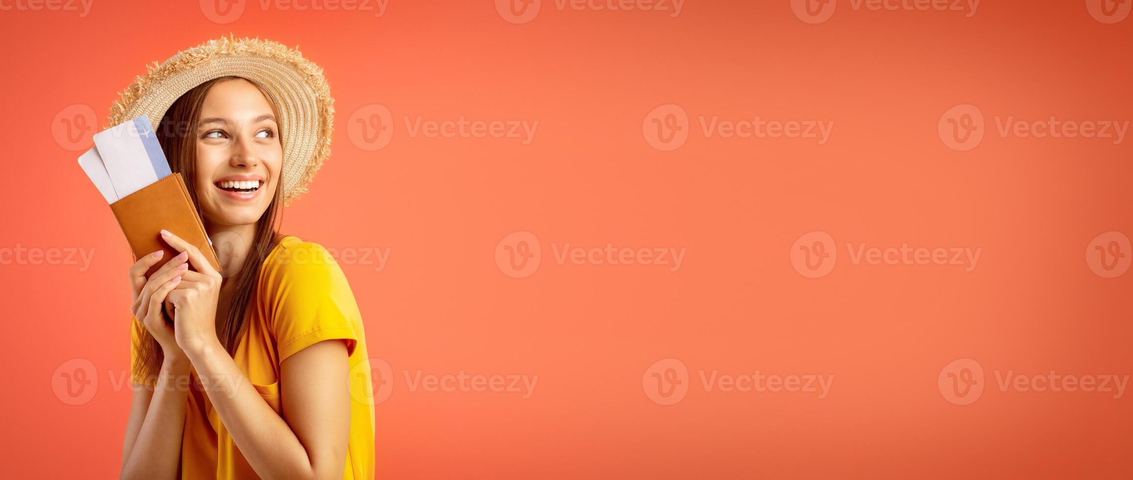Dreamy pretty girl with passport and flight tickets looking aside over yellow studio background photo