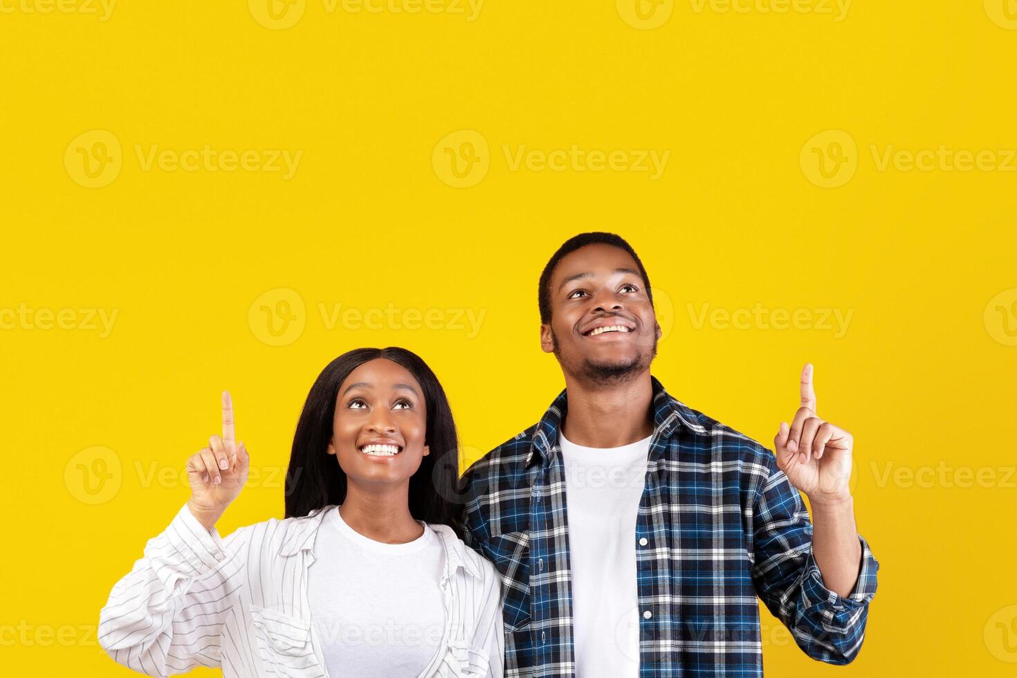 Great advertising offer, huge promotion and sale. Surprised millennial african american students guy and woman in casual look and show up with hands to free space, isolated on yellow background photo