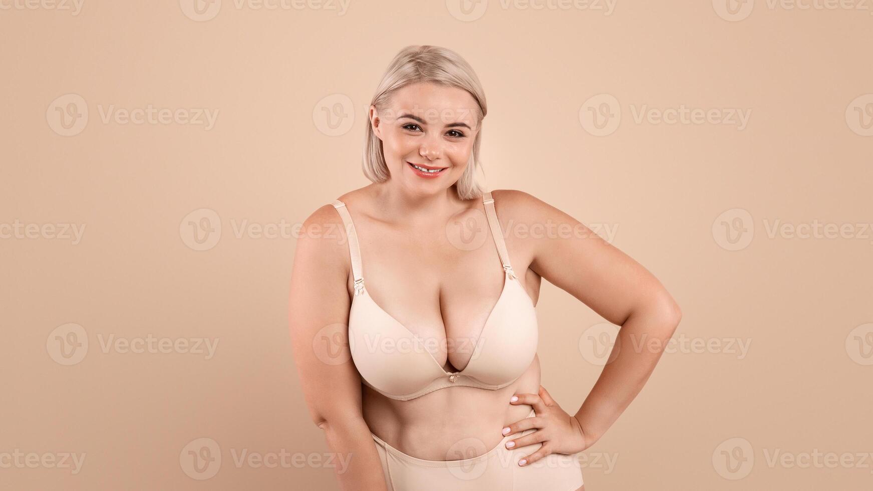 Plus Size Woman. Portrait Of Beautiful Curvy Body Positive Lady Posing In Underwear, Attractive Young Oversized Female In Lingerie Standing Over Beige Studio Background, Smiling At Camera, Copy Space photo