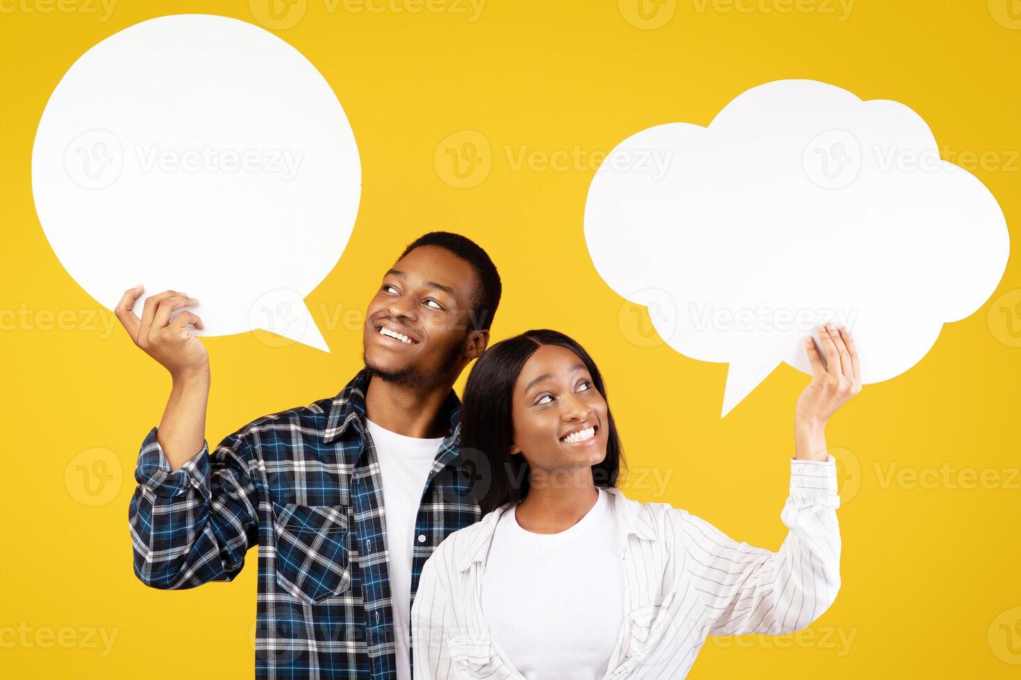 Different opinions in couple relationship. Cheerful pensive young african american guy and woman in casual look at abstract bubble for thoughts, isolated on yellow background, studio shot, free space photo