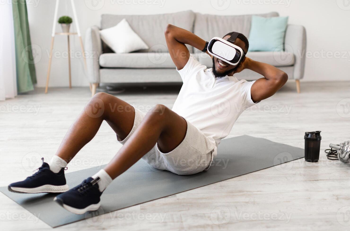 Virtual Workout. African Man Wearing VR Glasses Doing Abs Exercise At Home. Training Via Augmented Reality Application, Futuristic Fitness, Smart Sport And Technology Concept photo