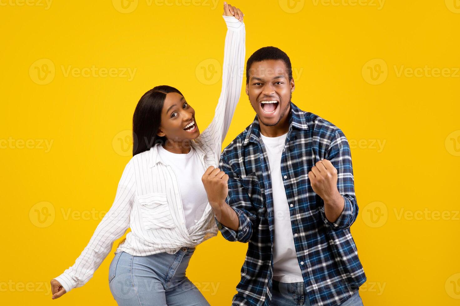 Emotions of victory, celebration and dance. Sincere expression of success young african american male and female with open mouth, screams and rejoices to win isolated on yellow background, studio shot photo