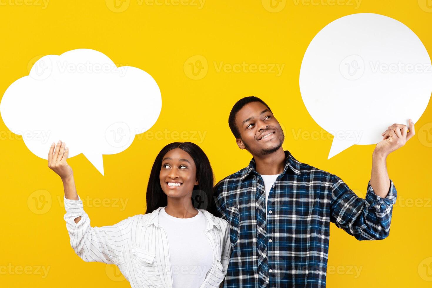 Different thoughts, dreams and empty place for words. Cheerful millennial african american couple of male and female holding abstract clouds with free space, isolated on yellow background, studio shot photo