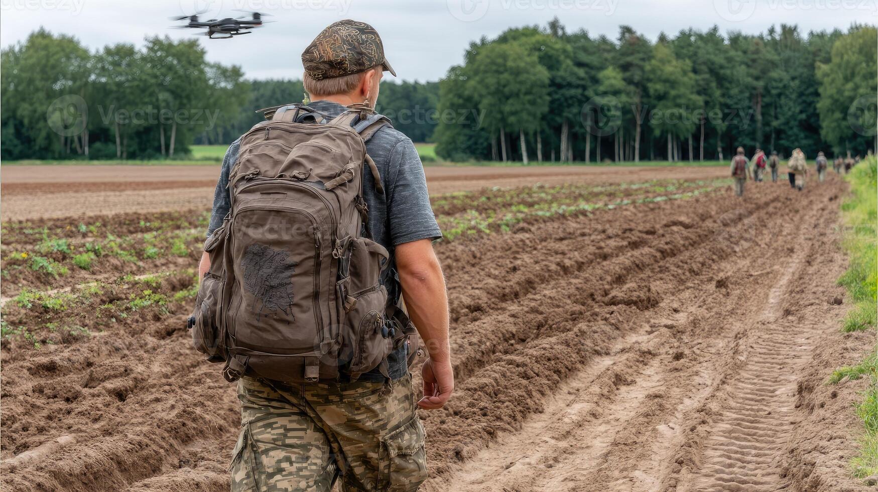 A man walking in a field with a backpack and a drone photo