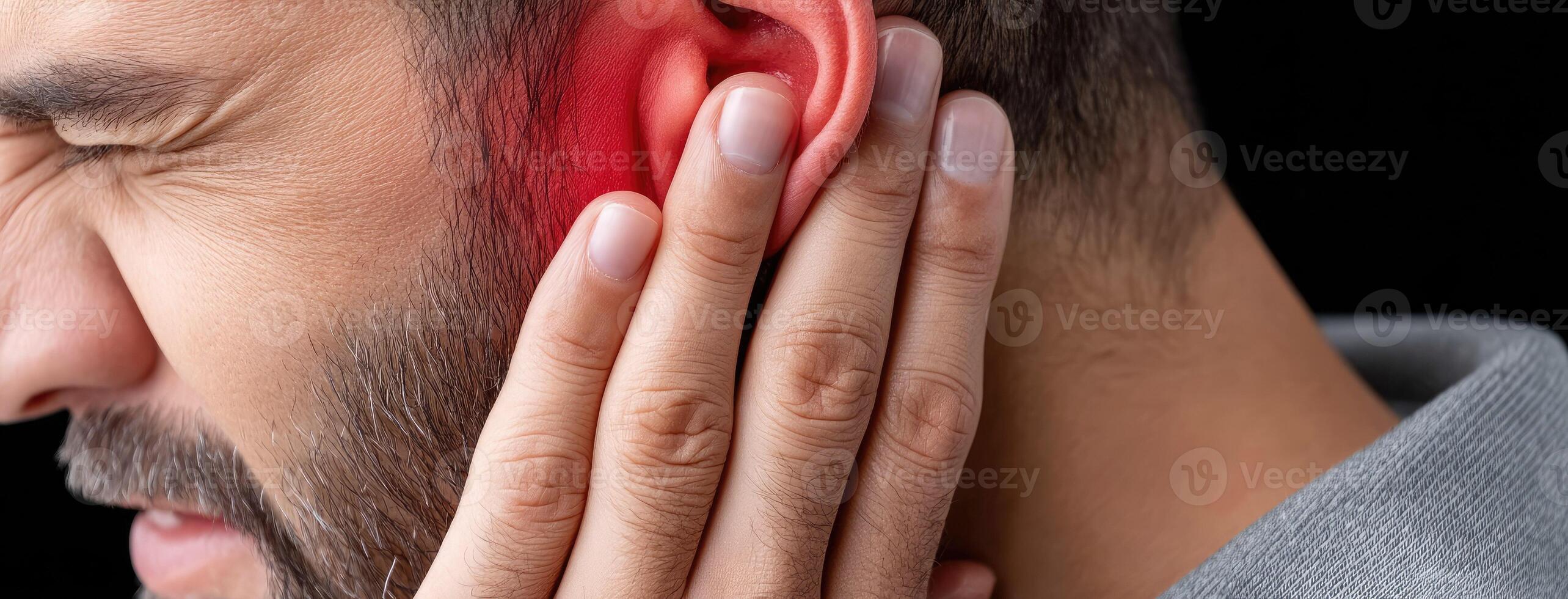 A man with a red ear is holding his ear photo