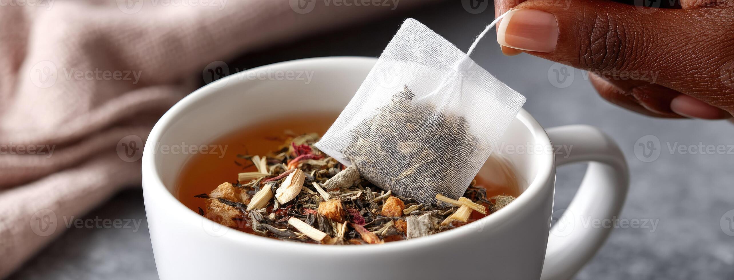 A person is holding a tea bag over a cup of tea photo