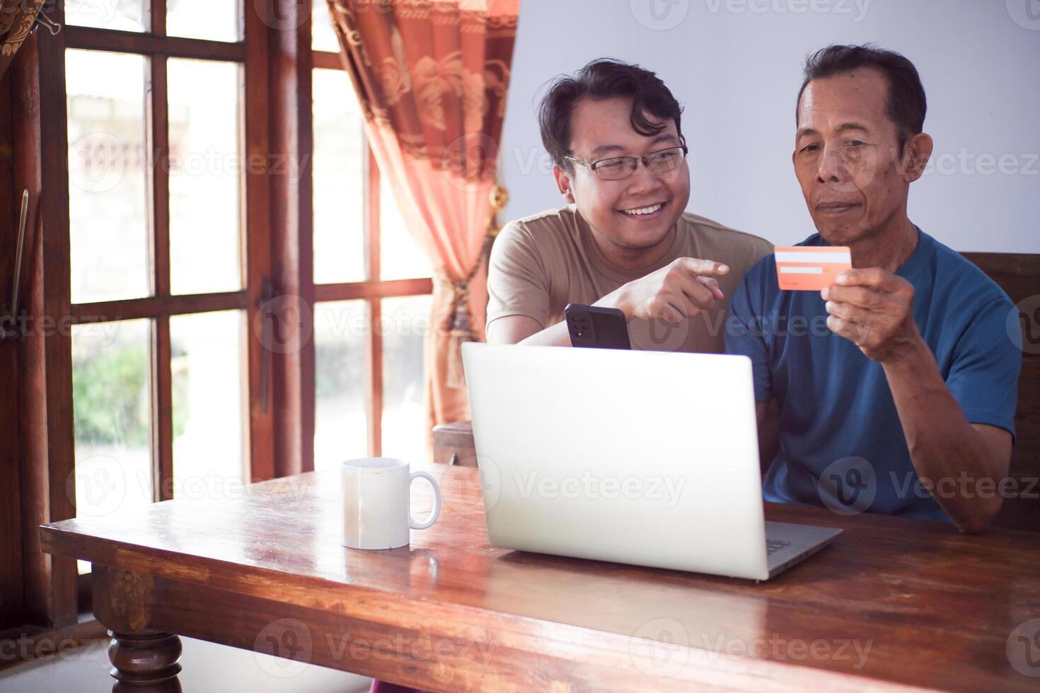 Happy son and old father pay online using laptop and credit card. Young and senior togetherness. Finance and Business Concept photo