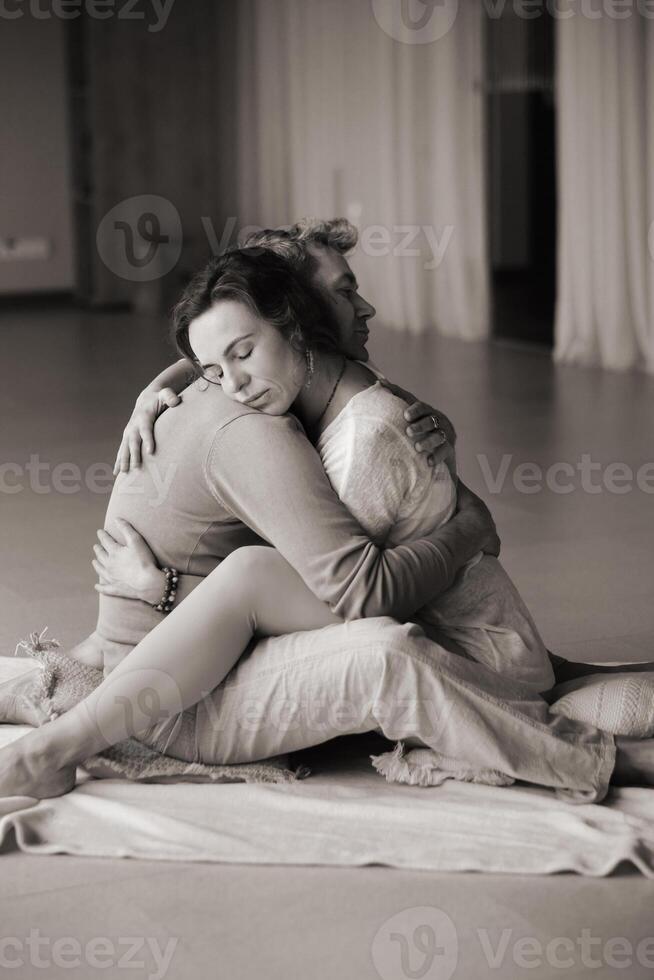 Couple practicing intimate hugging and emotional connection in a serene indoor space during a wellness retreat. photo
